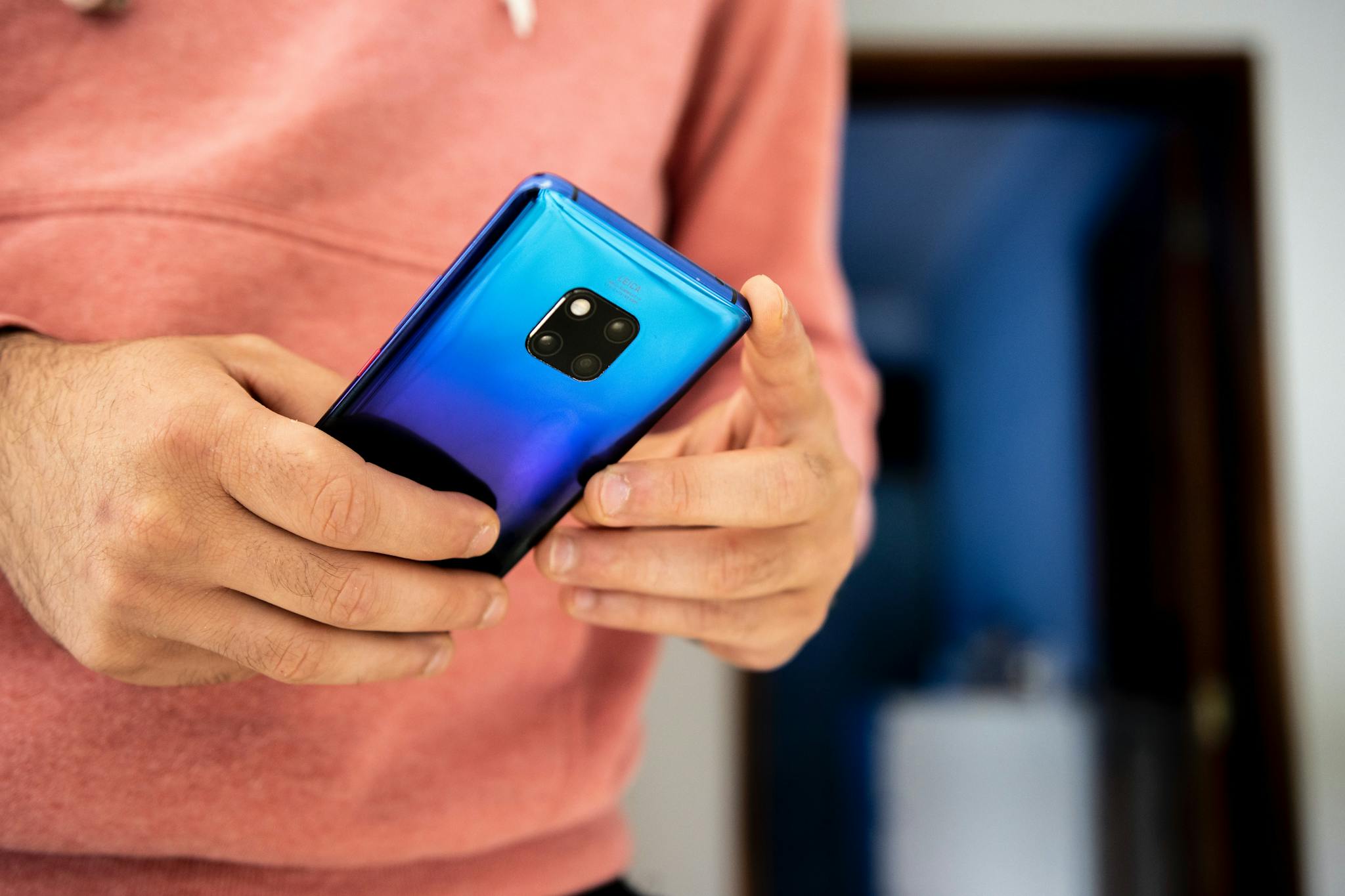 Close-up image of a person using a vibrant blue smartphone indoors.