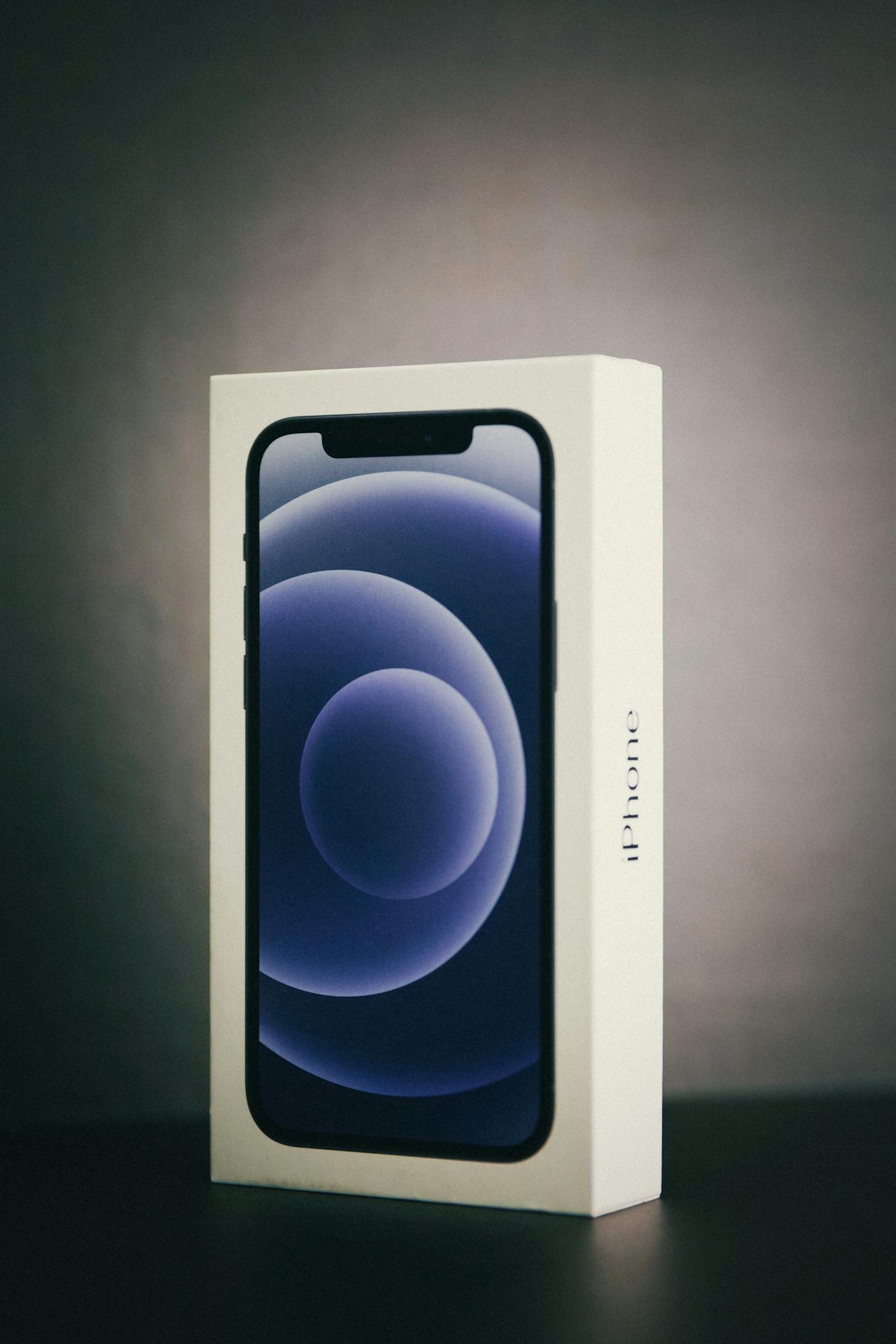 Modern smartphone in original box with gray studio background.